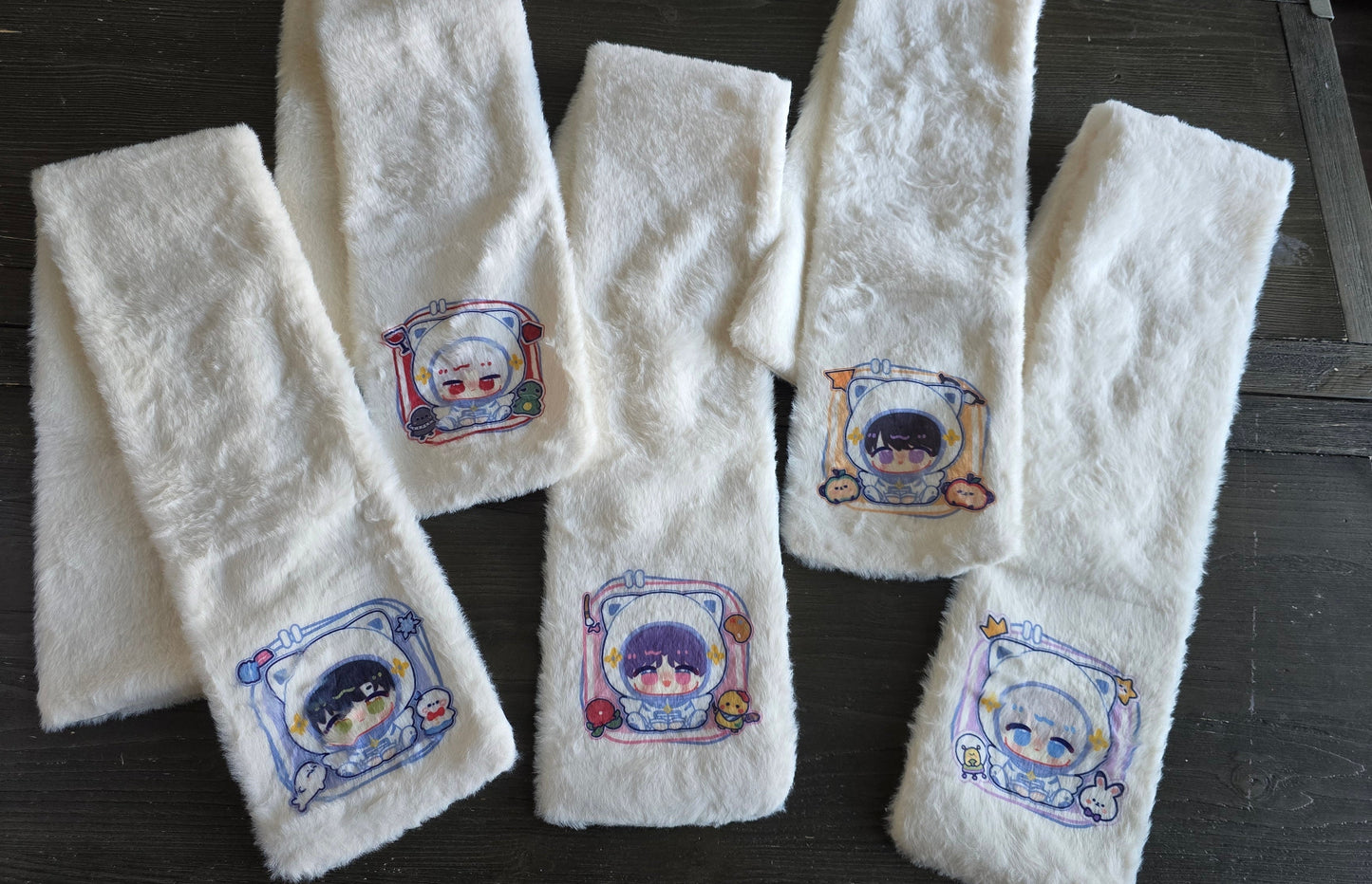 Set of white scarfs with printed designs of sylus, rafayel, caleb, zayne and xavier on a wooden surface